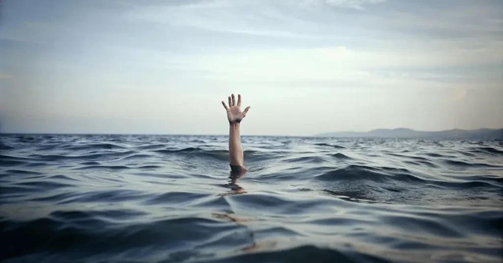A woman's hand is upward, and she is drowning in the sea